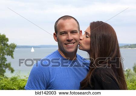 Caucasian woman kissing man outdoors View Large Photo Image Stock Image - Caucasian woman kissing man outdoors. Fotosearch