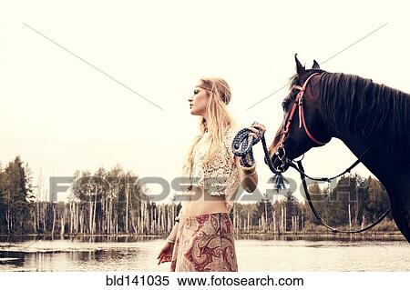 Caucasian woman leading horse near lake View Large Photo Image Stock Photography - Caucasian woman leading horse near lake. Fotosearch