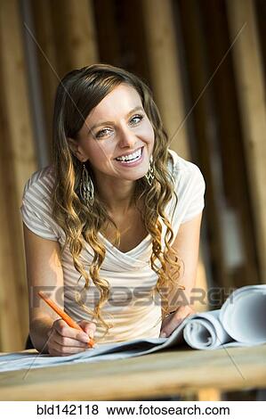 Caucasian woman marking blueprints in house under construction View Large Photo Image Stock Photo - Caucasian woman marking blueprints in house under construction. Fotosearch