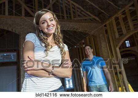 Stock Photograph - Caucasian woman smiling in house under construction. Fotosearch