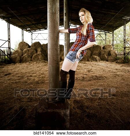 Picture - Caucasian woman standing on pole in barn. Fotosearch