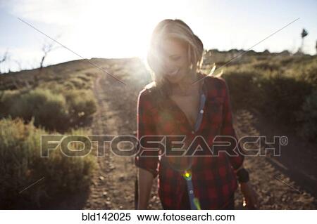 Stock Photography - Caucasian woman walking on dirt road. Fotosearch