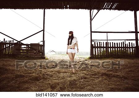 Stock Photo - Caucasian woman walking on hay in barn. Fotosearch
