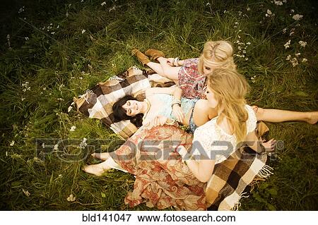 Stock Photo - Caucasian women relaxing in field. Fotosearch