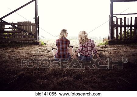 Stock Photography - Caucasian women sitting on hay in barn. Fotosearch