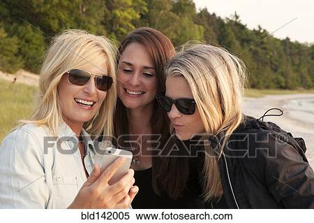 Stock Photography - Caucasian women using cell phone outdoors. Fotosearch
