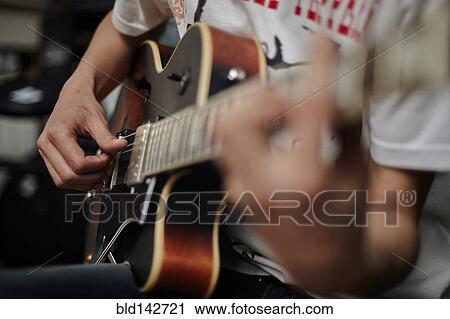 Stock Image - Close up of Caucasian man playing guitar. Fotosearch