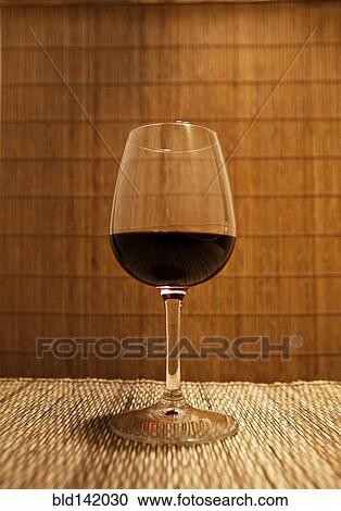 Stock Image - Close up of glass of red wine on table. Fotosearch