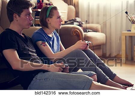 Stock Photograph - Couple playing video games on living room floor. Fotosearch