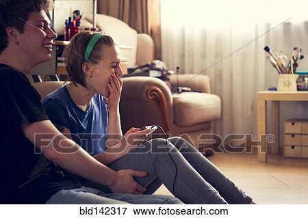 Stock Photo - Couple playing video games together on living room floor. Fotosearch