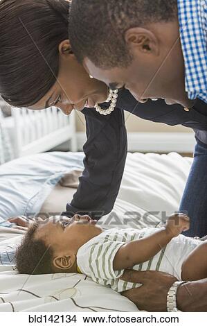 Picture - Couple playing with baby son on bed. Fotosearch
