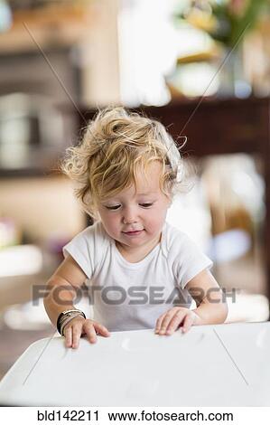 Stock Image - Curious Caucasian baby boy opening container. Fotosearch