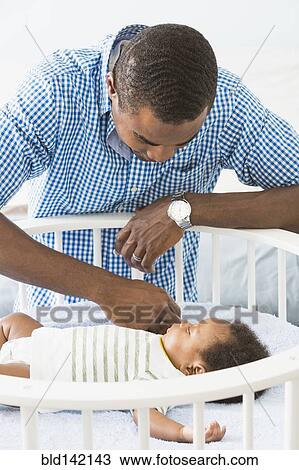 Father admiring sleeping baby son in crib View Large Photo Image Stock Image - Father admiring sleeping baby son in crib. Fotosearch