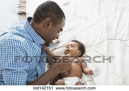 Stock Image - Father and baby son laying on bed. Fotosearch