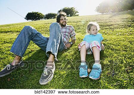 Stock Photo - Father and daughter laying in grassy field. Fotosearch