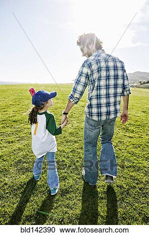 Father and daughter walking in grassy field View Large Photo Image Stock Image - Father and daughter walking in grassy field. Fotosearch