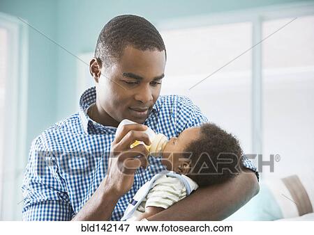 Father bottle feeding baby son View Large Photo Image Stock Photo - Father bottle feeding baby son. Fotosearch
