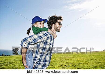 Father carrying daughter piggyback in grassy field View Large Photo Image Stock Image - Father carrying daughter piggyback in grassy field. Fotosearch