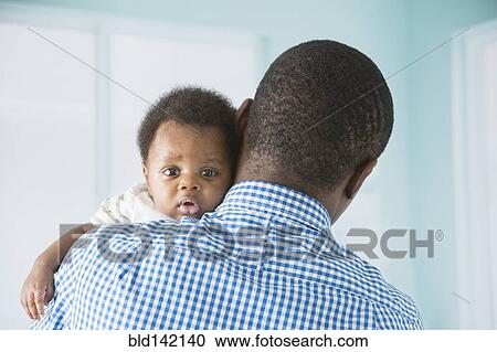 Stock Image - Father cradling baby son. Fotosearch