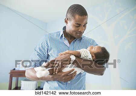 Stock Image - Father cradling baby son. Fotosearch