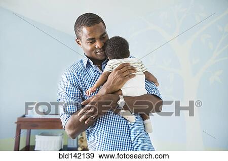 Stock Photo - Father cradling baby son. Fotosearch