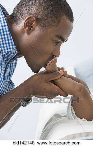 Stock Photo - Father kissing feet of baby son. Fotosearch
