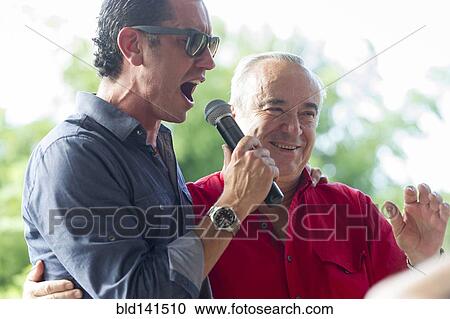 Grandfather and grandson talking into microphone at family reunion View Large Photo Image Stock Image - Grandfather and grandson talking into microphone at family reunion. Fotosearch