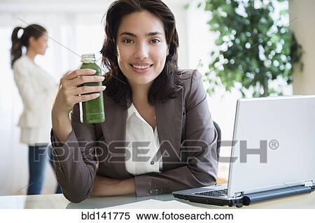 Hispanic businesswoman drinking green juice at desk in office View Large Photo Image Stock Photography - Hispanic businesswoman drinking green juice at desk in office. Fotosearch