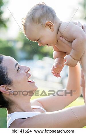 Hispanic mother holding baby outdoors View Large Photo Image Picture - Hispanic mother holding baby outdoors. Fotosearch