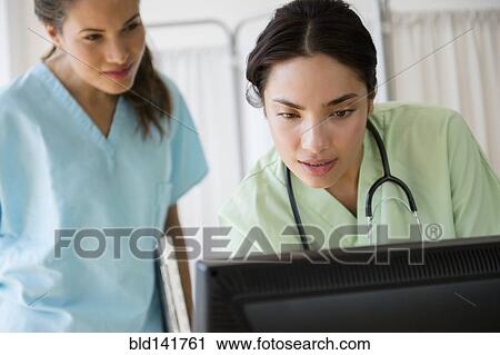 Stock Image - Hispanic nurses working together on computer at hospital. Fotosearch
