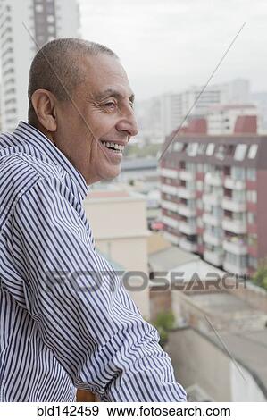 Hispanic senior man admiring cityscape from balcony View Large Photo Image Stock Photo - Hispanic senior man admiring cityscape from balcony. Fotosearch