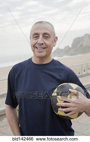 Hispanic senior man carrying soccer ball by beach View Large Photo Image Stock Photograph - Hispanic senior man carrying soccer ball by beach. Fotosearch