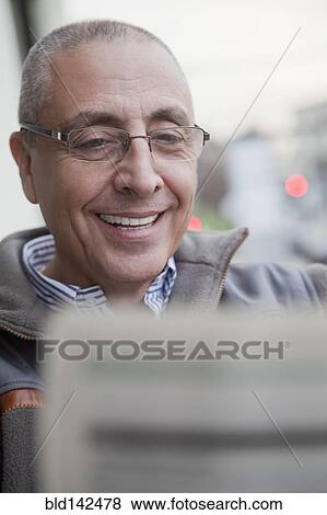 Stock Photo - Hispanic senior man reading newspaper. Fotosearch