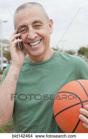 Hispanic senior man with basketball talking on cell phone View Large Photo Image Picture - Hispanic senior man with basketball talking on cell phone. Fotosearch