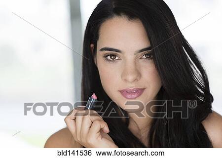 Hispanic woman applying lipstick View Large Photo Image Stock Photograph - Hispanic woman applying lipstick. Fotosearch