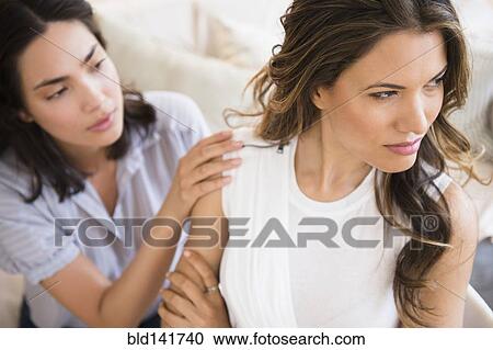 Stock Image - Hispanic woman comforting angry friend. Fotosearch