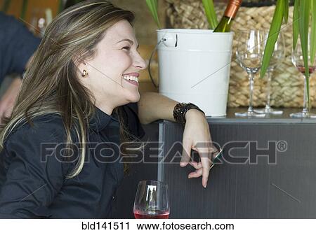 Stock Image - Hispanic woman drinking glass of wine at party. Fotosearch