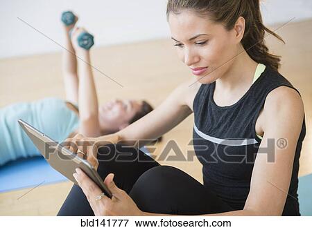 Hispanic woman using digital tablet in yoga studio View Large Photo Image Stock Photo - Hispanic woman using digital tablet in yoga studio. Fotosearch