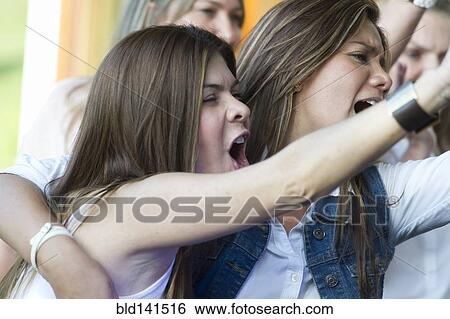 Stock Photograph - Hispanic women cheering at concert. Fotosearch