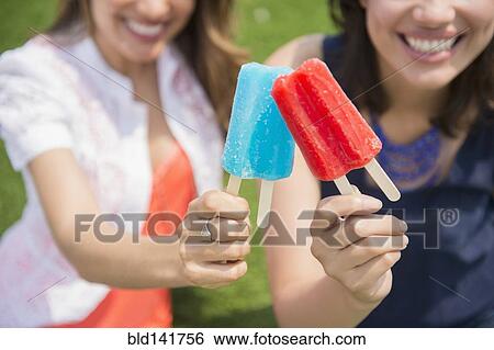 Hispanic women eating popsicles outdoors View Large Photo Image Stock Photograph - Hispanic women eating popsicles outdoors. Fotosearch