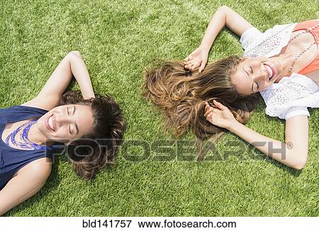 Stock Photo - Hispanic women laying in grass outdoors. Fotosearch
