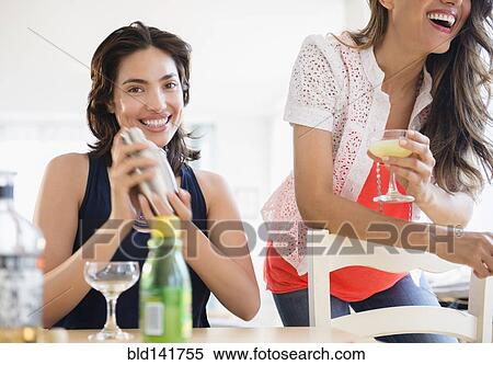 Stock Photography - Hispanic women mixing cocktails at party. Fotosearch