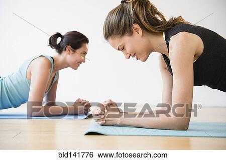 Stock Photograph - Hispanic women practicing yoga in studio. Fotosearch