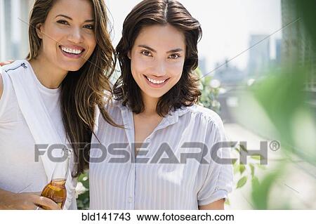 Stock Image - Hispanic women relaxing together outdoors. Fotosearch