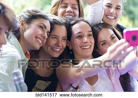 Stock Photo - Hispanic women taking selfie at family reunion. Fotosearch