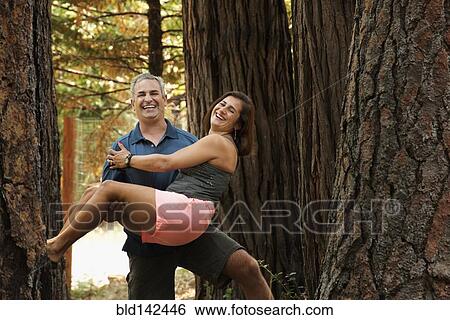 Stock Photograph - Husband carrying wife in forest. Fotosearch