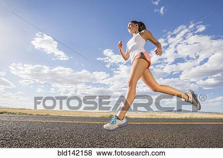 Low angle view of Caucasian woman running on remote road View Large Photo Image Stock Photo - Low angle view of Caucasian woman running on remote road. Fotosearch
