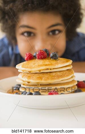 Mixed race boy admiring plate of pancakes and berries View Large Photo Image Stock Photo - Mixed race boy admiring plate of pancakes and berries. Fotosearch