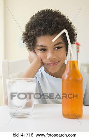 Mixed race boy choosing between soda and water View Large Photo Image Stock Photograph - Mixed race boy choosing between soda and water. Fotosearch