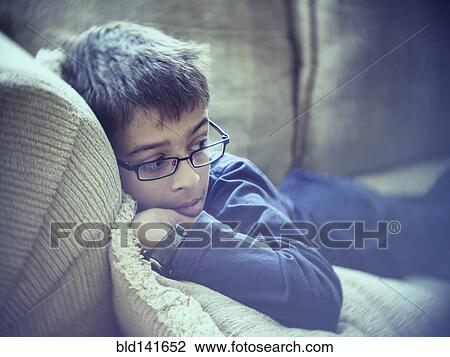 Stock Image - Mixed race boy laying on sofa. Fotosearch